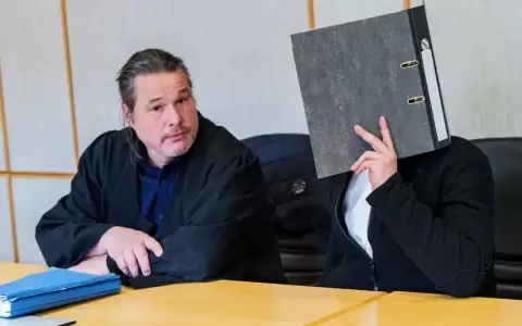 El acusado (der.) cubre su rostro durante la audiencia, en la que estuvo acompa�ado por su abogado defensor (izq.)