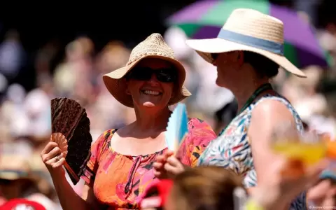 Mujeres que asisten como p�blico al torneo de tenis de Wimbledon se abanican.