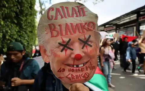 Un manifestante sostiene un cartel con el rostro caricaturizado del presidente estadounidense Donald Trump.