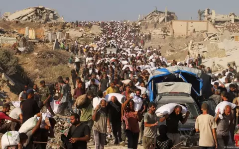 Una multitud de palestinos cargan a pie con alimentos y otros bienes de ayuda humanitaria en Beit Lahia, en el norte de la Franja de Gaza.