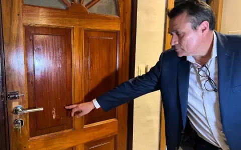 El comunicador Carlos Javier Ben�tez muestra el impacto de bala en la puerta de su vivienda.