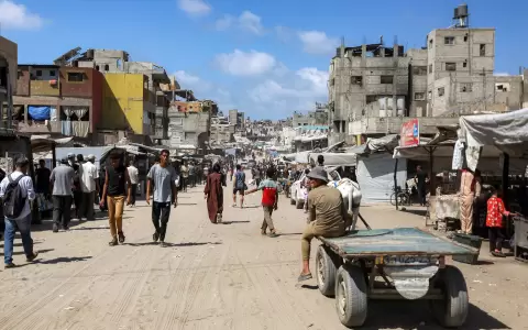 La gente camina junto a edificios da�ados a lo largo de una calle en Khan Yunis, en el sur de la Franja de Gaza.
