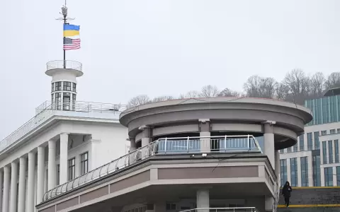 Banderas de Ucrania y Estados Unidos ondean sobre la Universidad Americana de Kiev mientras una mujer baja las escaleras de la Plaza Postal de Kiev.
