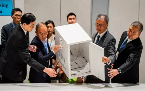 El secretario de Asuntos Constitucionales y Continentales, Erick Tsang Kwok-wai, ayuda a vaciar la primera urna tras cierre del escrutinio.