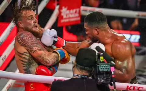 Jake Paul (izq) recibiendo un derechazo de Anthony Joshua (der).