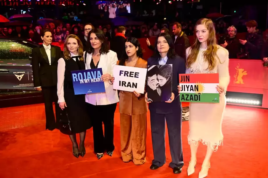 La actriz germano-iran� Jasmin Tabatabai y sus invitados sostienen carteles de "Ir�n libre" y "Rojava" en la alfombra roja de la Berlinale.