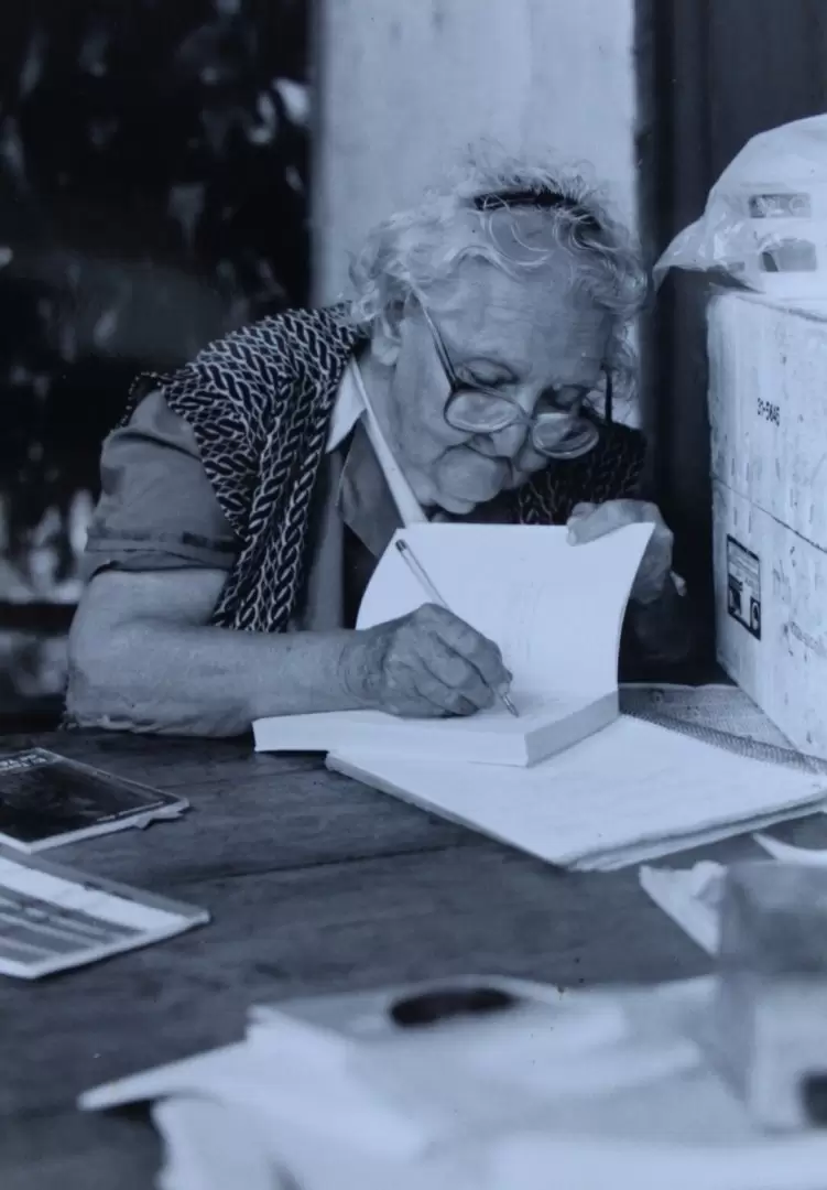 Josefina Plá dedicando un libro suyo en el patio de su casa, ca. 1990. Cortesía