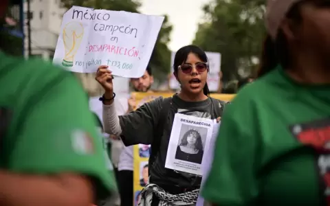 Una integrante del colectivo "Madres Buscadoras" sostiene un cartel de protesta mientras marcha hacia el Estadio Azteca antes de la apertura.