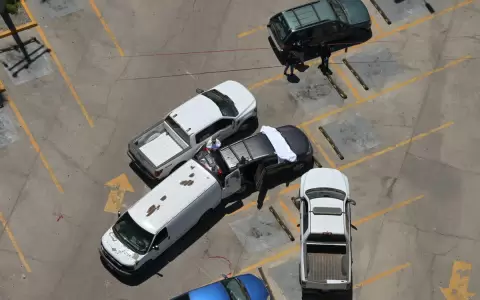 Vista a�rea de trabajadores forenses inspeccionando un autom�vil donde se hall� un cuerpo en un estacionamiento frente al estadio Caliente.