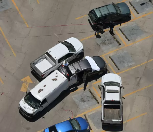 Vista a�rea de trabajadores forenses inspeccionando un autom�vil donde se hall� un cuerpo en un estacionamiento frente al estadio Caliente.